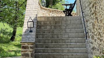 Un escalier en pierre mène à un espace extérieur abrité, aménagé avec une table et des chaises.