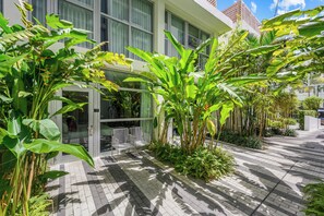 A modern building with a glass entrance, surrounded by lush greenery and a paved walkway. - The Fairwind Hotel (Miami Beach)