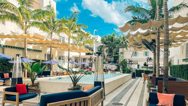 A poolside area with lounge seating, umbrellas, and palm trees. - The Fairwind Hotel (Miami Beach)
