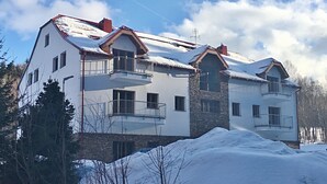 Ein mehrstöckiges Gebäude mit Balkonen, einer Stein-Fassade und verschneiter Umgebung.