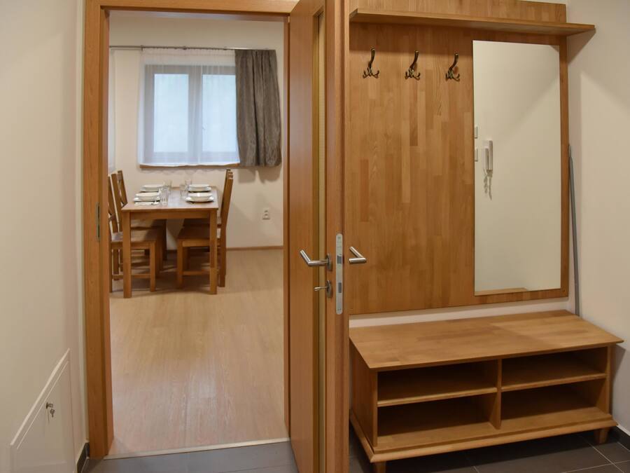 A room with a wooden wardrobe, a dining table with chairs, and a window with curtains.