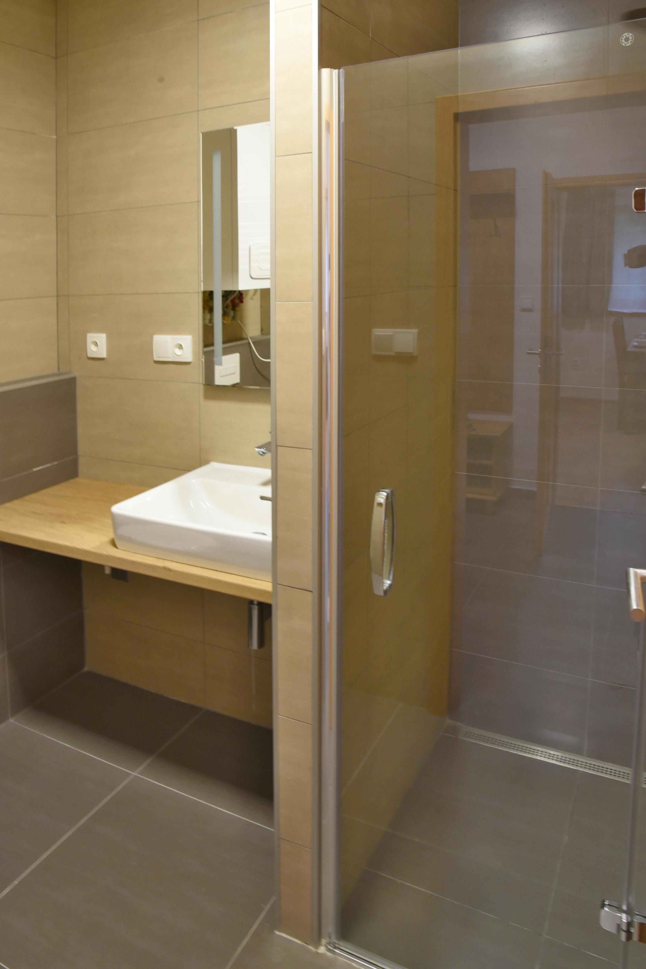 Un baño moderno con cabina de ducha de vidrio, tocador de madera y espejo sobre el lavabo.