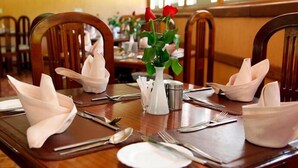 A dining table set with folded napkins, silverware, and a vase with a red rose. - Gracia Gardens (Nairobi)