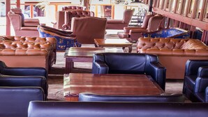 A seating area with leather sofas and armchairs, a wooden coffee table, and a patterned rug. - Gracia Gardens (Nairobi)