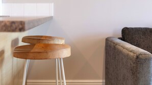 A bar stool with a wooden top and metal legs, a gray upholstered armchair, and a white tiled backsplash. - Elliot Suite No2 - Donnini Apartments (Ayr)