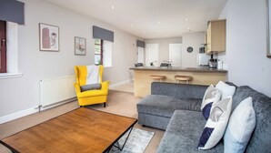 A modern living room with a sofa, a yellow armchair, and a wooden coffee table. - Elliot Suite No2 - Donnini Apartments (Ayr)