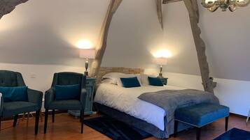 Une chambre à coucher avec un grand lit, deux fauteuils, une table de chevet et un lustre.