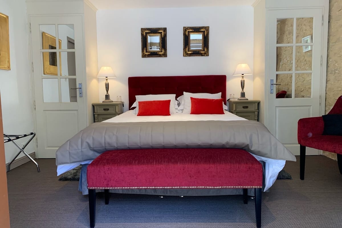 A neatly arranged bedroom with a large bed, two bedside tables, a bench, and two wall-mounted mirrors.