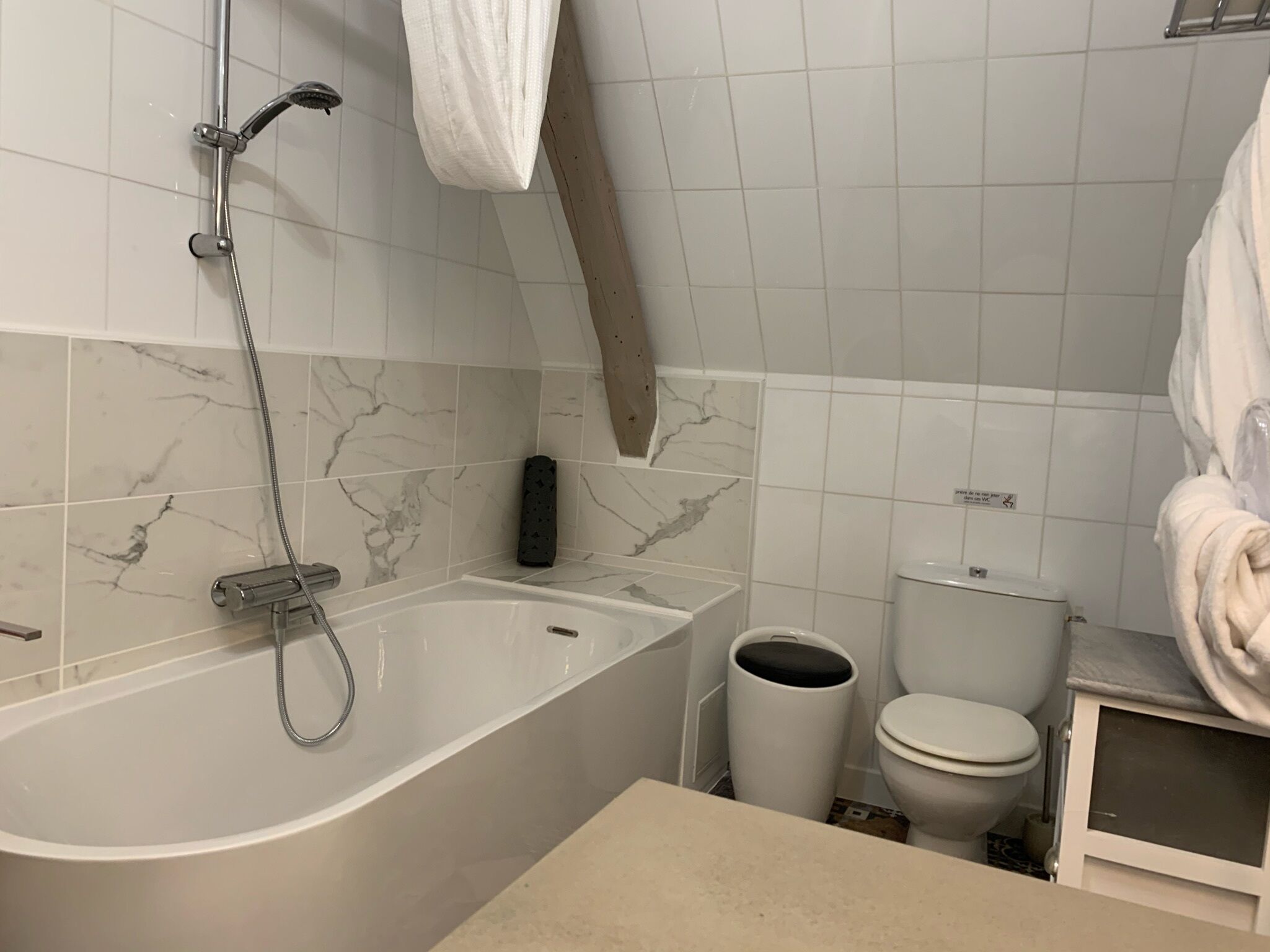 Et badeværelse med badekar, toilet og et håndklædestativ.