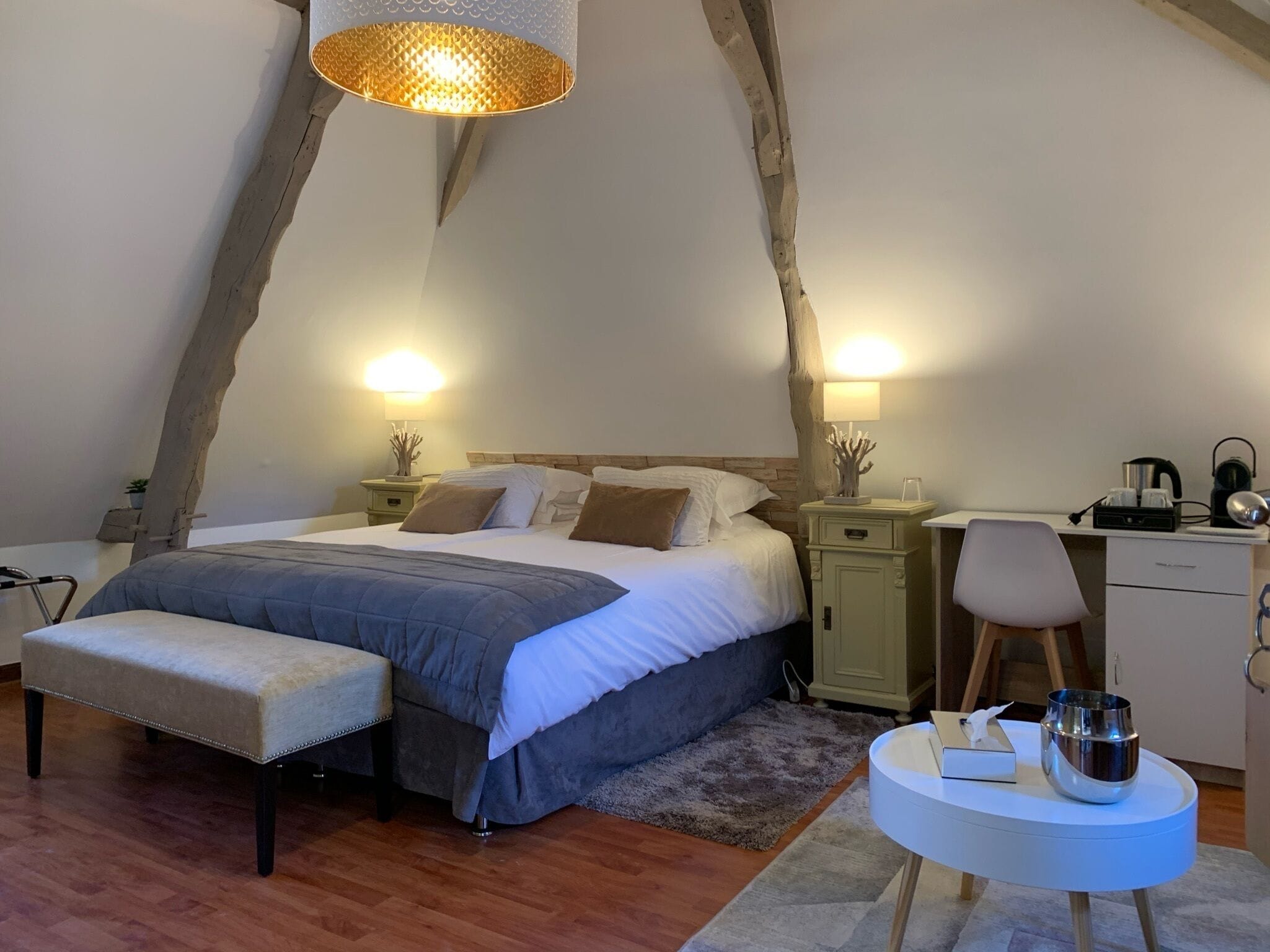 Una camera da letto accogliente con un letto grande, una panca, una scrivania e un lampadario.