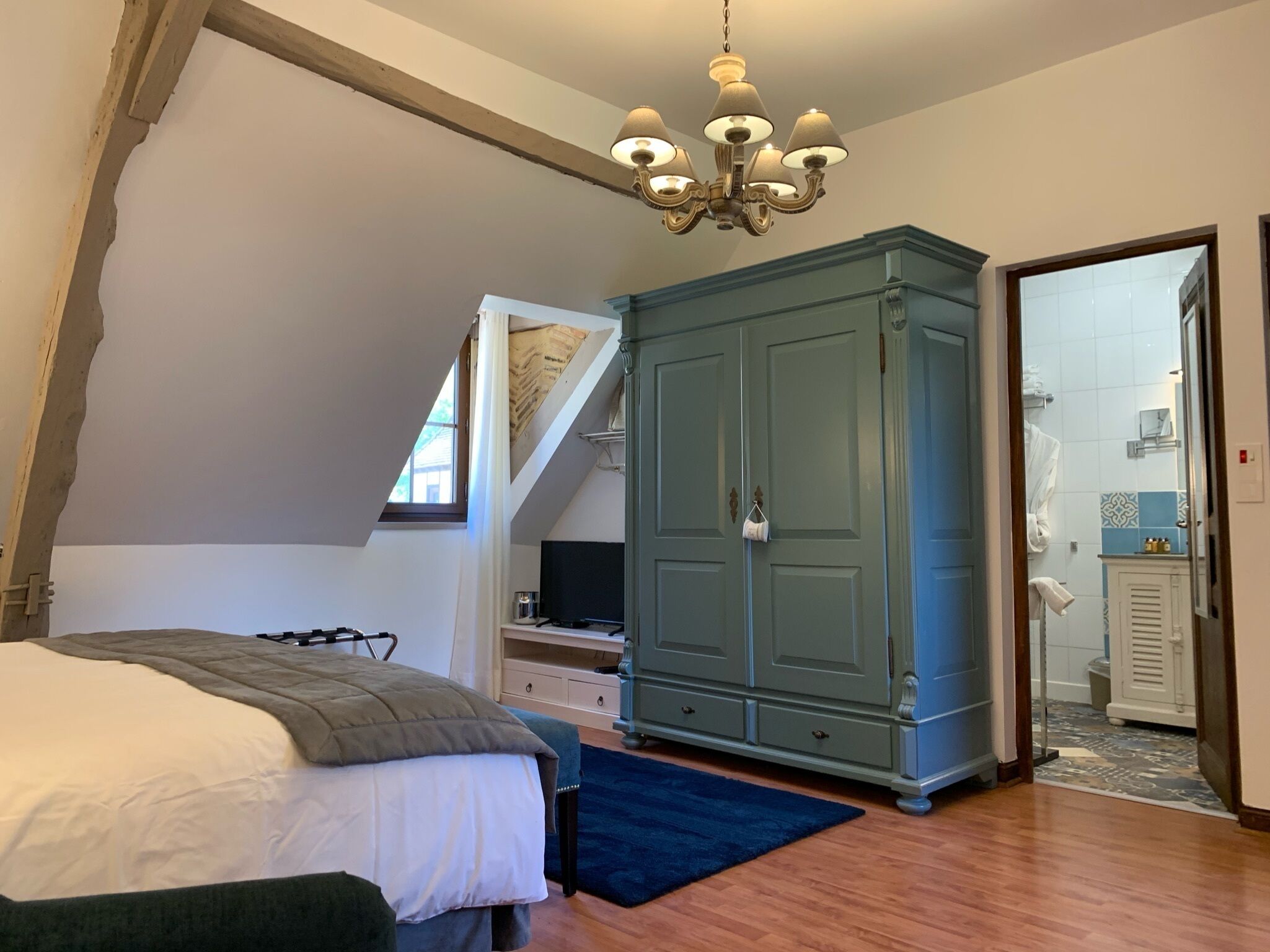 Een slaapkamer met een bed, een kledingkast, een bureau en een raam.