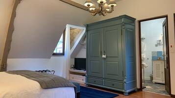 A bedroom with a bed, a wardrobe, a desk, and a window.