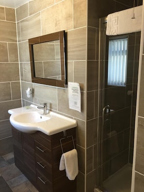 Un baño con lavamanos, espejo y cabina de ducha de vidrio.