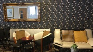 A living room with a sofa, chairs, a table, a mirror, and a patterned wall. - Glenheath Hotel (Blackpool)