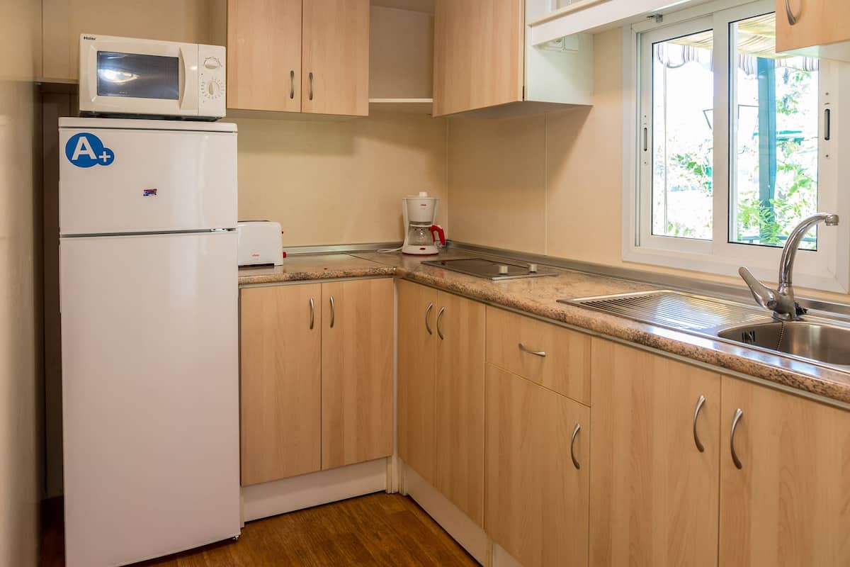 A compact kitchen with a refrigerator, microwave, and a coffee maker.