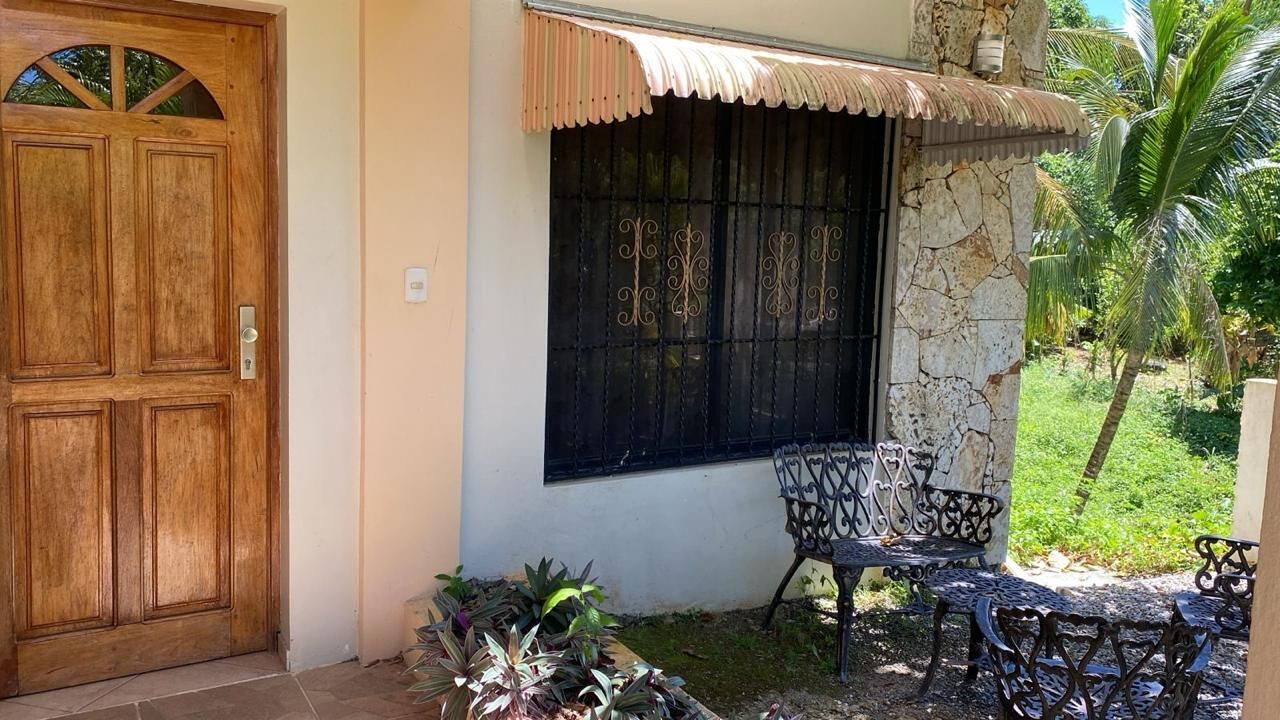 A wooden door, a stone wall, a window with decorative bars, and outdoor furniture.