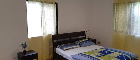 A bedroom with a single bed, a bedside table, and a small potted plant.