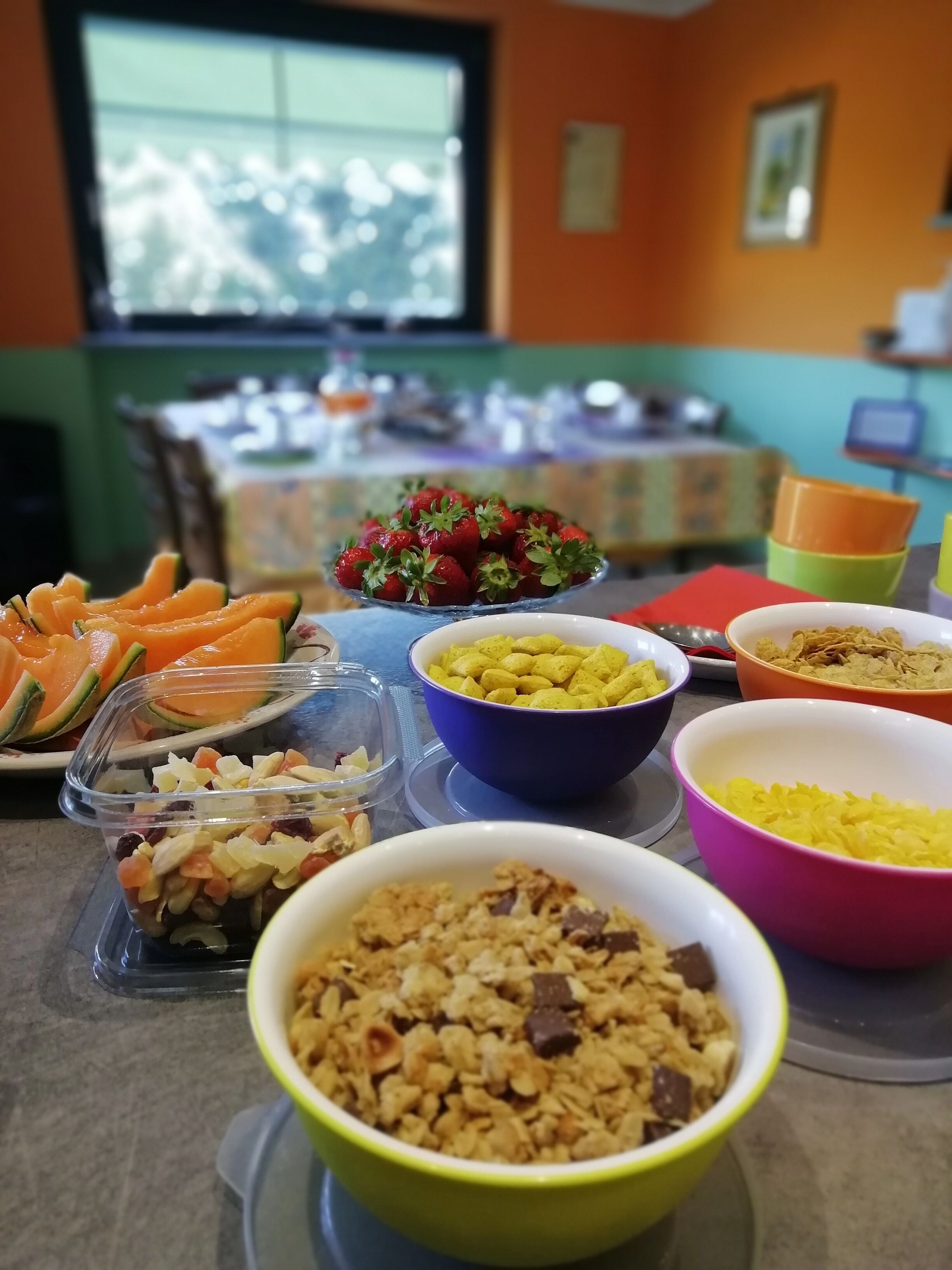 Una mesa con diversos alimentos, incluyendo tazones de cereal, frutas y aperitivos.