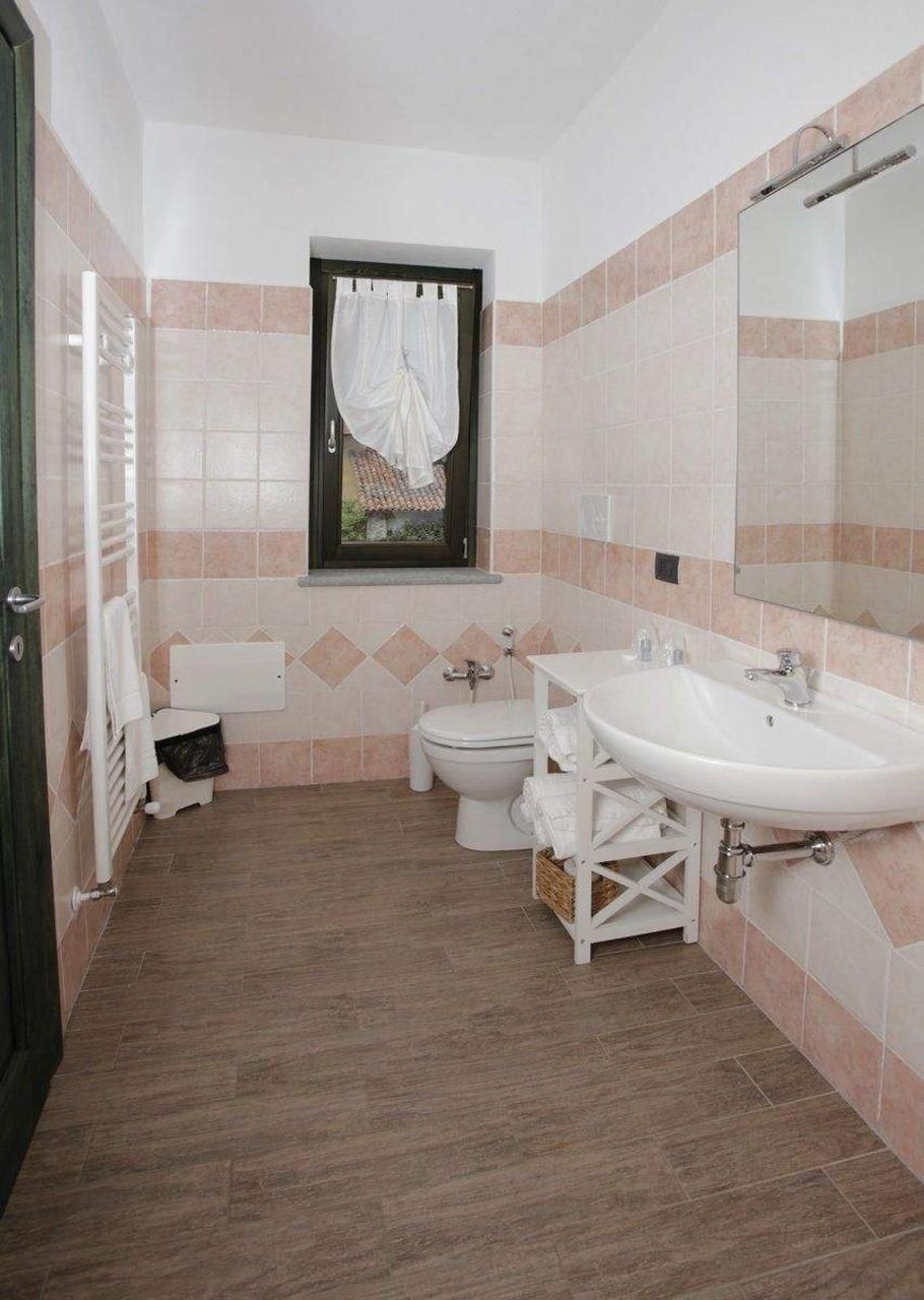 Une salle de bain avec deux lavabos, des toilettes et une fenêtre avec un rideau.