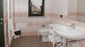 Une salle de bain avec deux lavabos, des toilettes et une fenêtre avec un rideau.