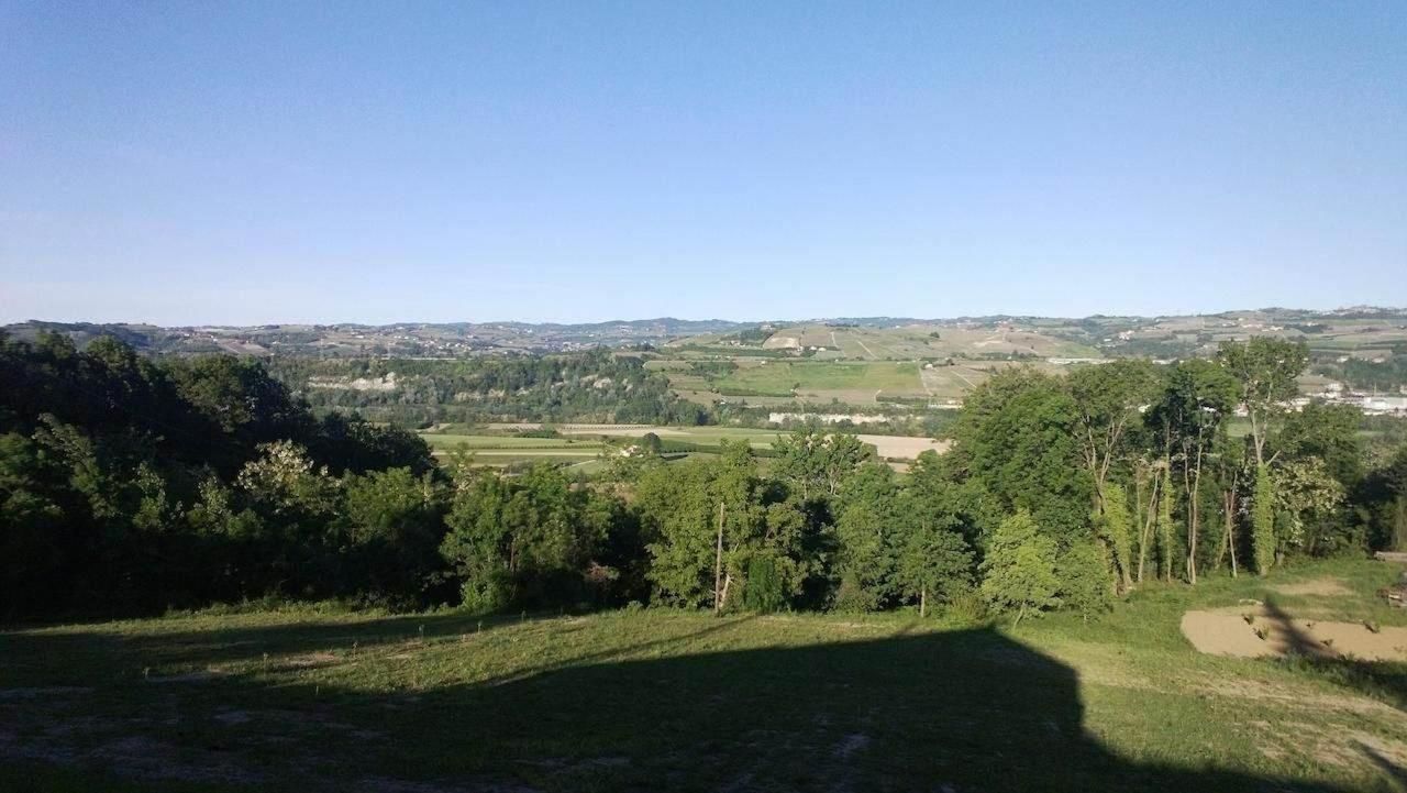 A panoramic view of a rural landscape with rolling hills, dense forests, and scattered buildings.