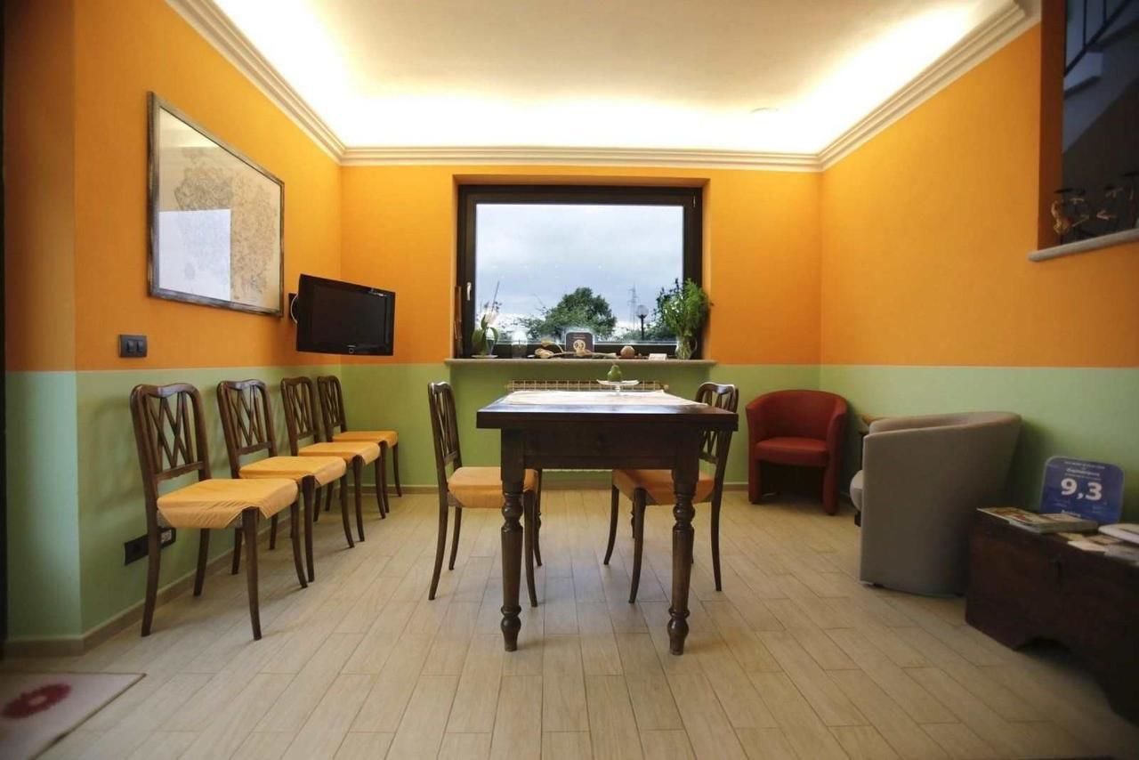 A dining area with a table and chairs, a television on the wall, and a window with a view.