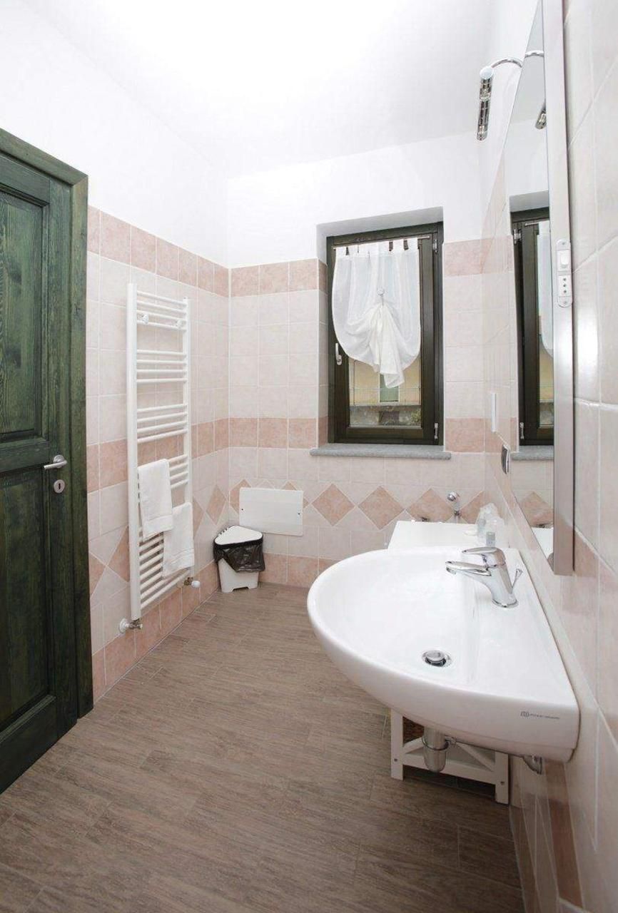 Une salle de bain avec un lavabo, un miroir, un porte-serviettes et une fenêtre.