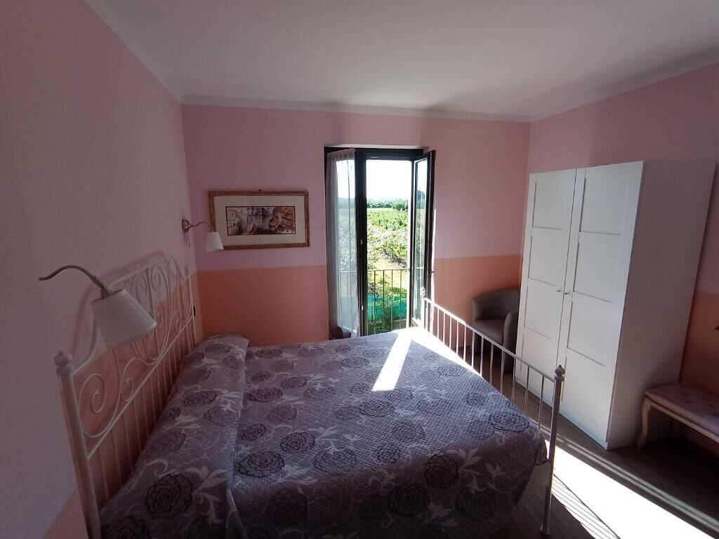 Ein Schlafzimmer mit einem Bett, einem Kleiderschrank, einer Bank und einer Tür, die auf einen Balkon führt.