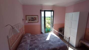 Ein Schlafzimmer mit einem Bett, einem Kleiderschrank, einer Bank und einer Tür, die auf einen Balkon führt.