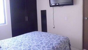 A bedroom with a bed, a wardrobe, and a TV mounted on the wall. - Casa Villa R (Mazatlán)