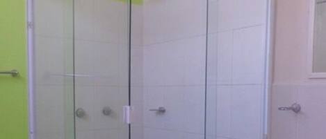 A bathroom with a glass shower enclosure, a toilet, and a sink.