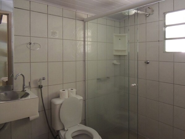Un baño con inodoro, lavamanos y ducha con mampara de vidrio.