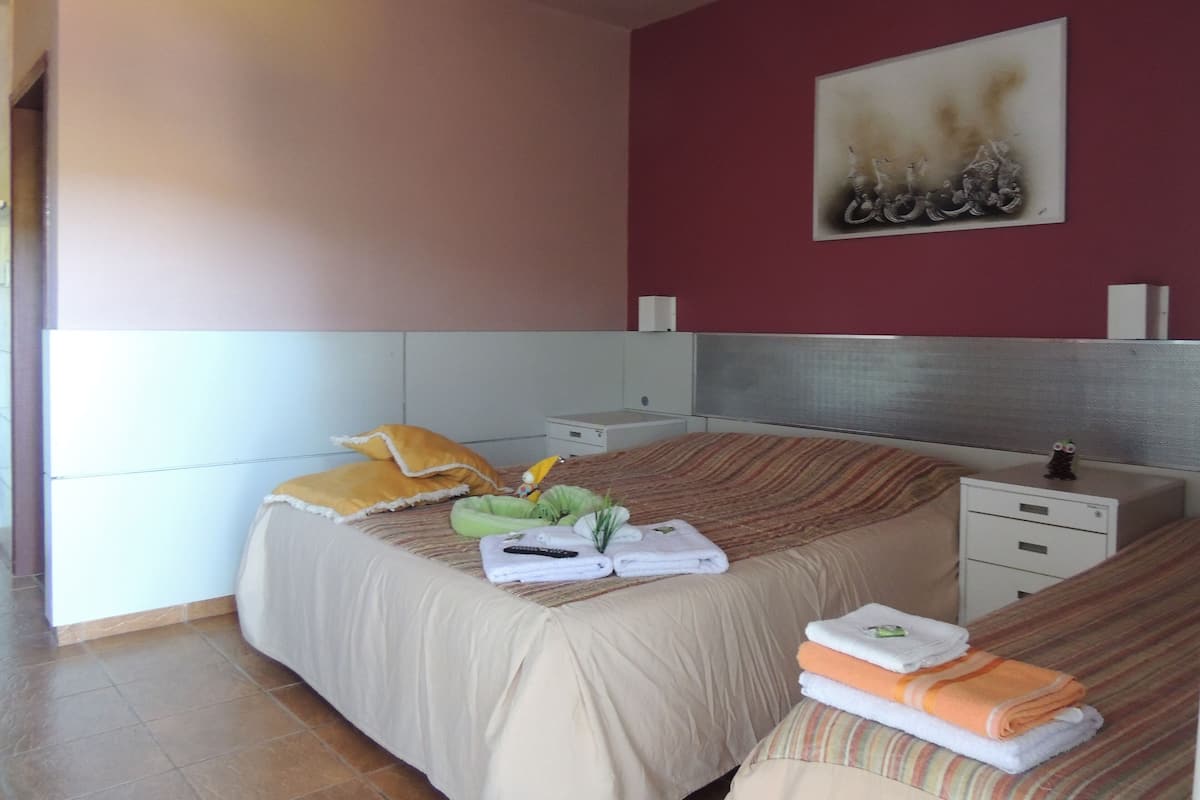 A bedroom with a bed, bedside tables, a nightstand, and a painting on the wall.