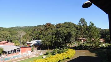Vista de um hotel com piscina, rodeado por vegetação exuberante e colinas.