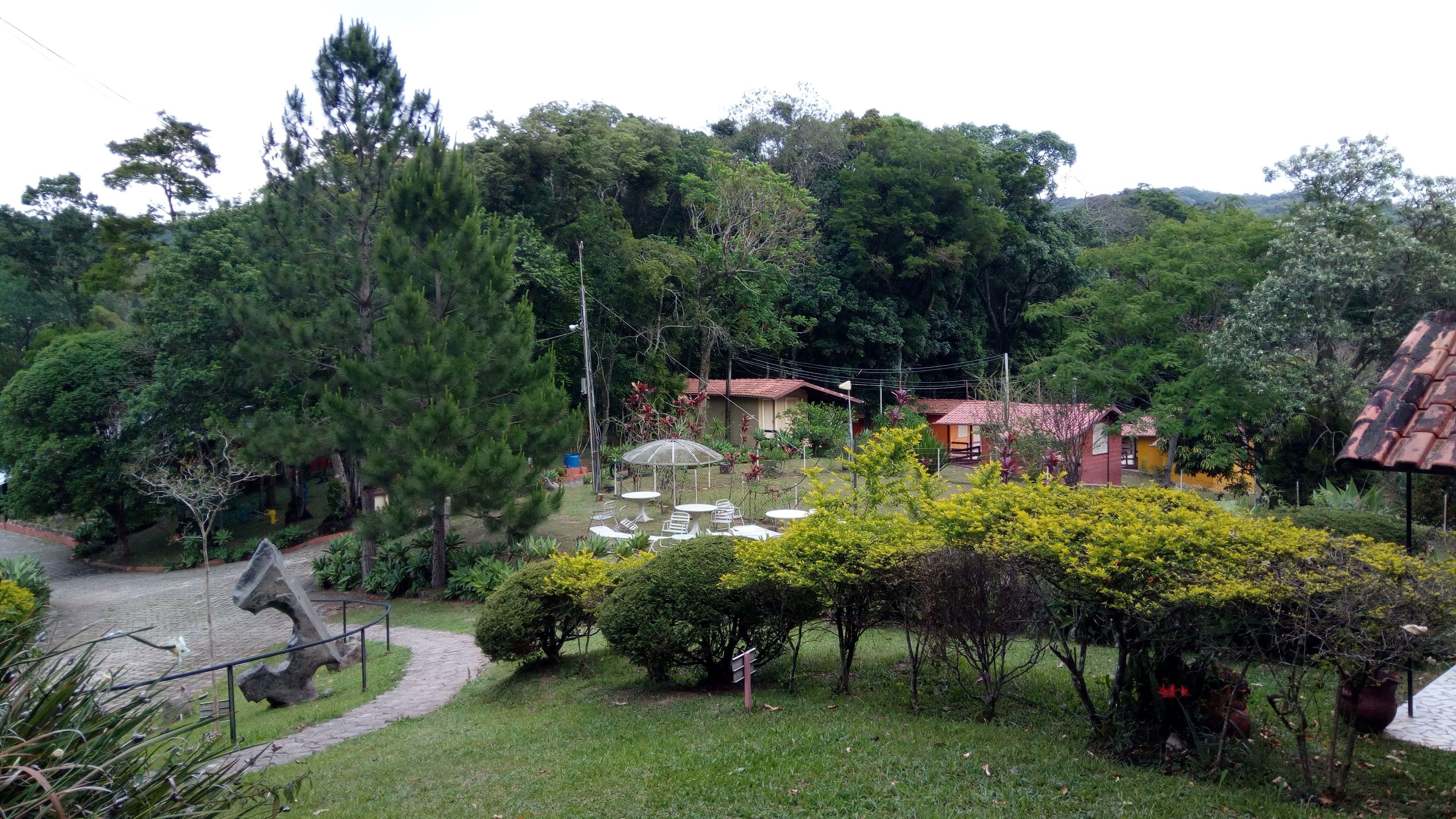 Un jardín con un camino empedrado, mobiliario exterior y un pequeño edificio con techo rojo.