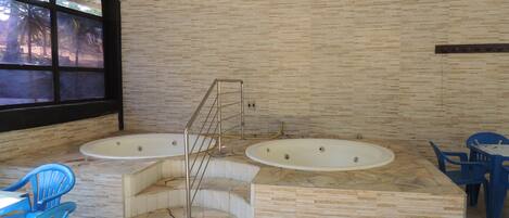 Un área de spa con dos jacuzzis, una escalera y sillas azules.