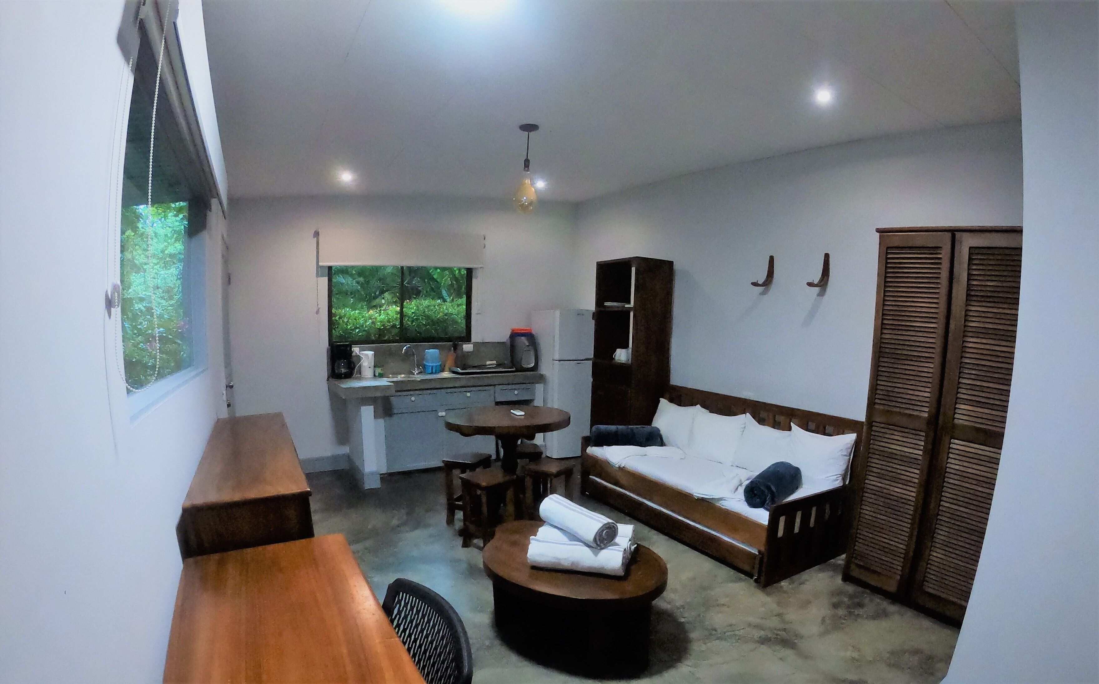 A compact living space with a kitchenette, a sofa, a dining table, and a small round table.