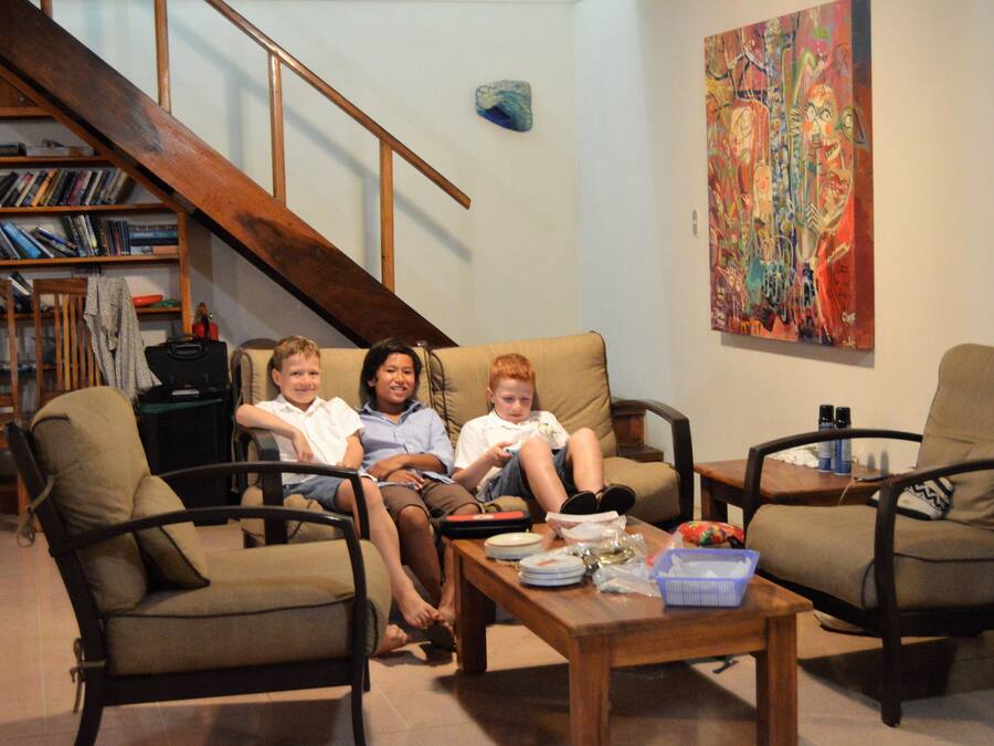 A living room with a staircase, a bookshelf, and a colorful painting on the wall.