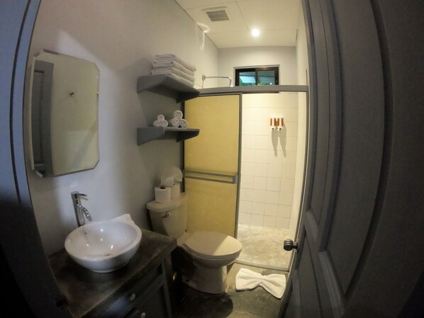 Un baño pequeño con lavabo, inodoro y zona de ducha.