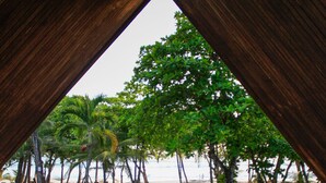 Vista de una playa desde una estructura de madera con barandilla, palmeras y una playa de arena.