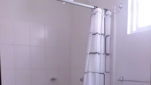 A bathroom with a shower, toilet, and a window. - Condo Maple (Mazatlán)