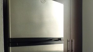 A stainless steel refrigerator with a freezer compartment, located in a kitchen with dark cabinets and white tiled flooring. - Condo Maple (Mazatlán)