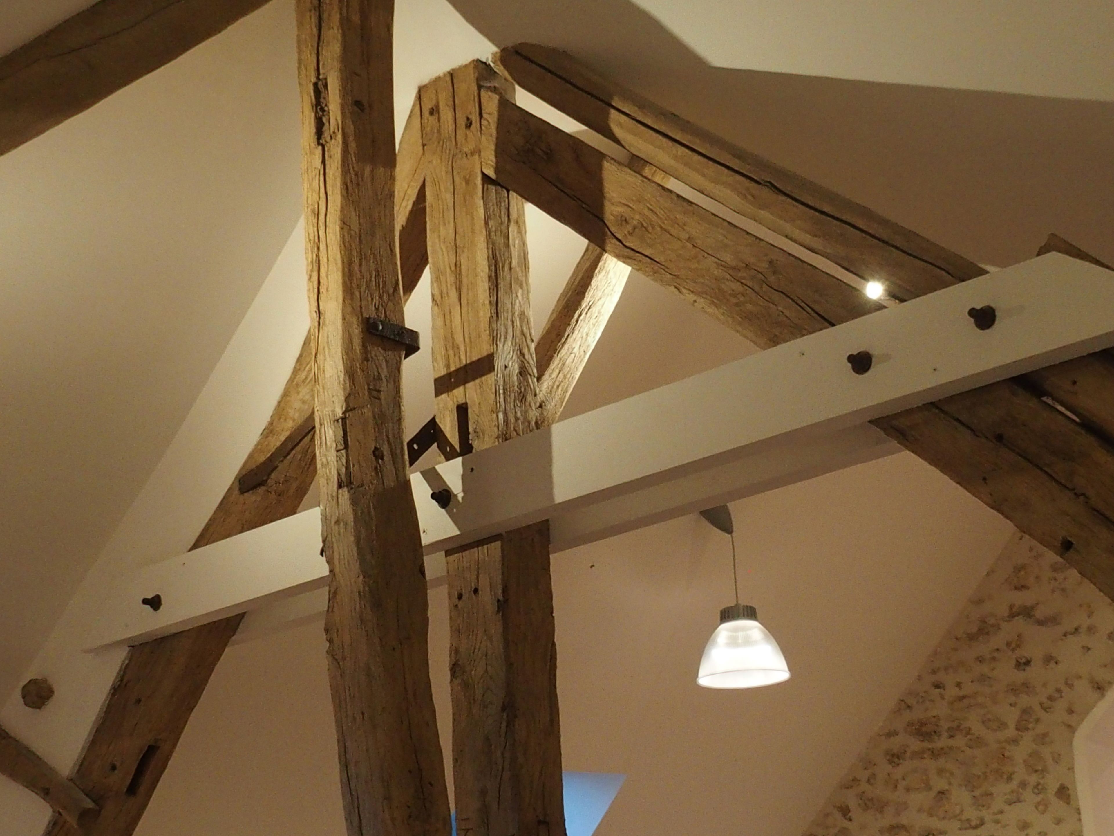 A room with exposed wooden beams and a hanging light fixture.