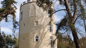 A tower-like building with a rounded top, multiple windows, and a central entrance. - Domaine de la Geneste (Châteaufort)