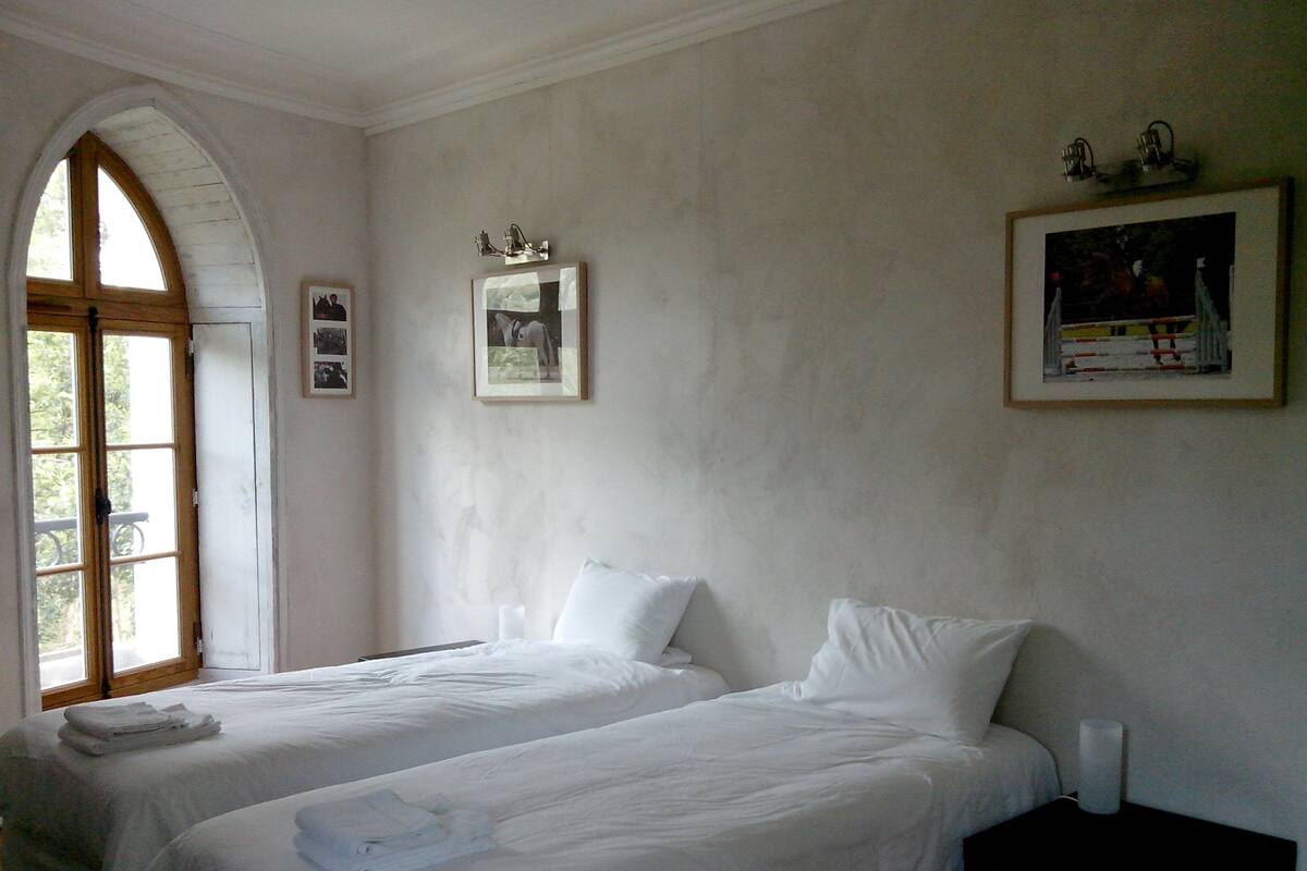 A room with two beds, a wooden door, and a window.