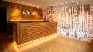 Un comptoir d’accueil avec un revêtement en bois et une enseigne indiquant « THE LODGE ».