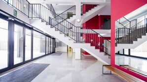 Un intérieur moderne avec un escalier, des portes vitrées et un mur d’accent rouge.
