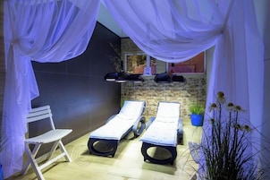 Un área de spa con dos sillones reclinables, una silla blanca y una planta en maceta.