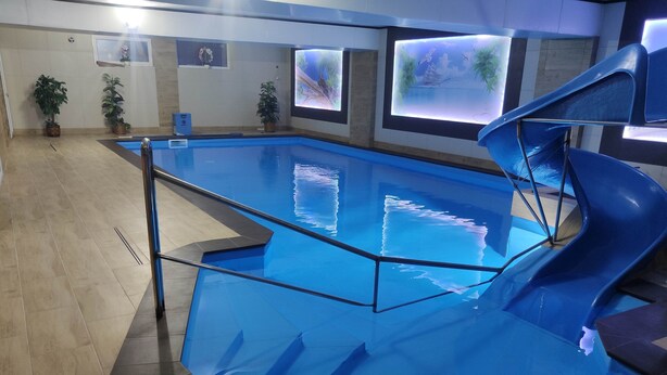 A swimming pool with a glass barrier, surrounded by tiled flooring and potted plants. - OW Sargus (Wladyslawowo)