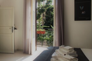 A hotel room with a bed, a door, and a view of the outside balcony. - Palazzo Cutelli LGBTQ House (Palermo)